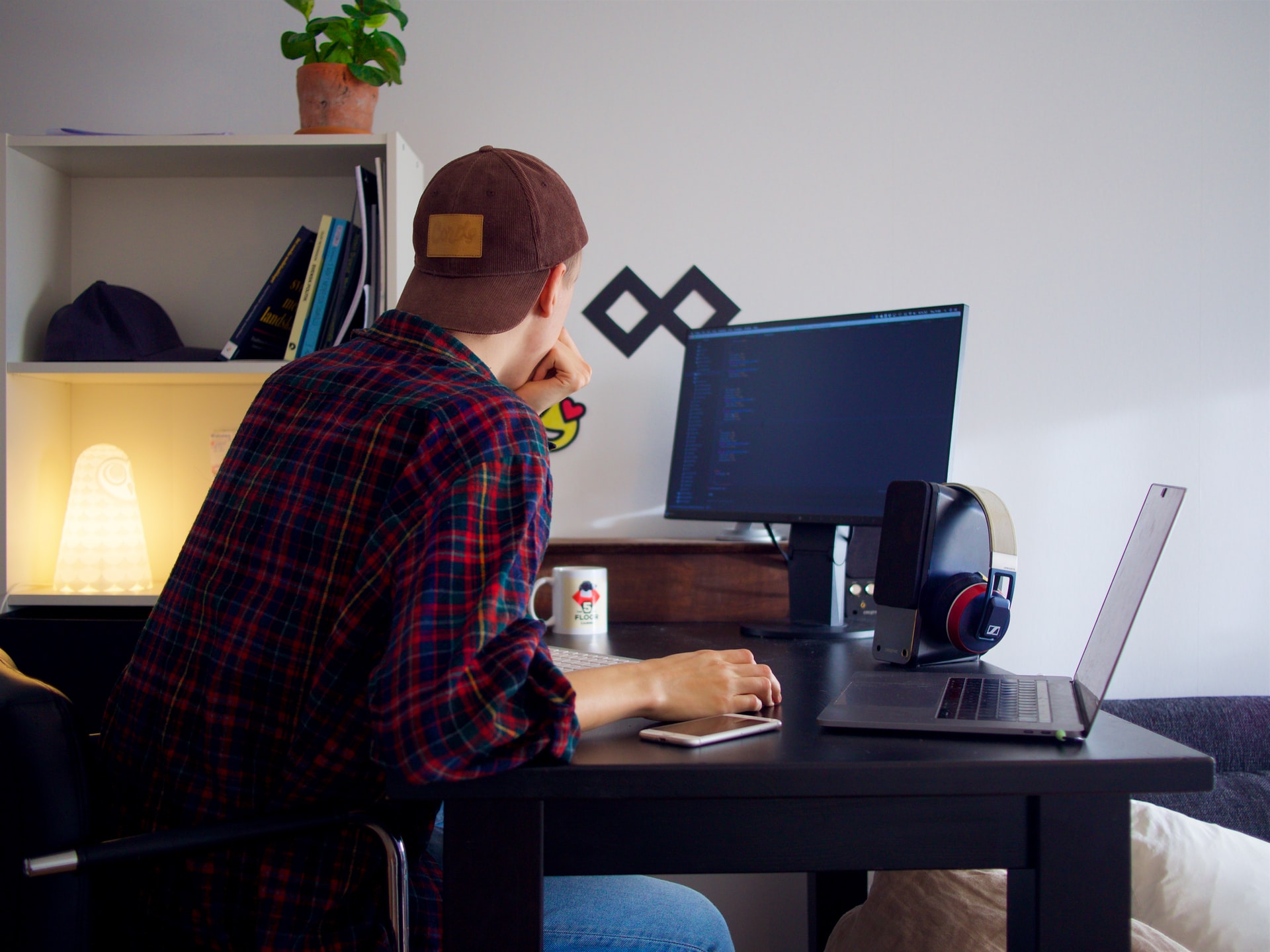 Solo founder alone at desk with laptop and external monitor.